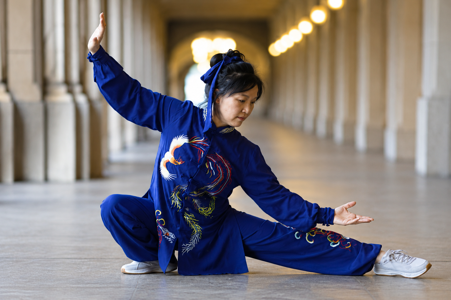Jin Hee Muren performing a low Tai Chi stance in a blue embroidered uniform